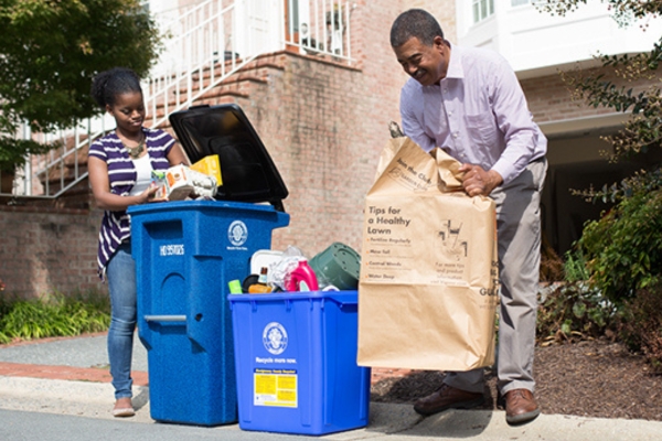 man and girl placing recyclables curbside