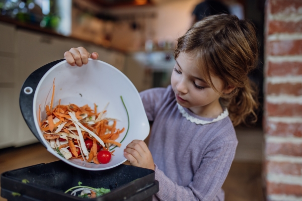 girl placing food scraps in container
