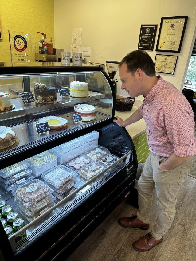 理事會主席Glass在向日葵麵包店觀看烘焙食品的展示櫃。