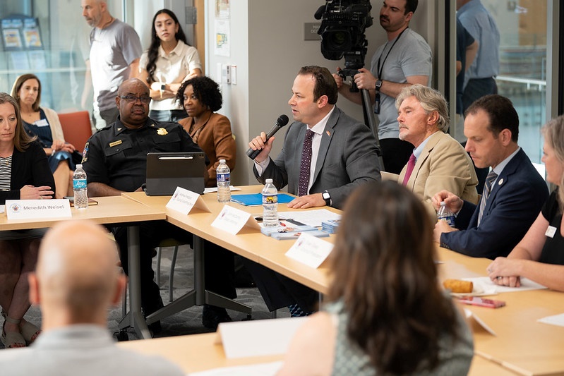 理事會主席Friedson在反仇恨工作小組會議上發表演說。 他坐在警察局長Marcus Jones和州檢察官John McCarthy中間。