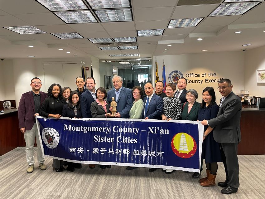 Des dirigeants du comté de Montgomery et de la ville de Xi’an posent devant une banderole intitulée « Sister Cities » (Villes jumelles) à Rockville.