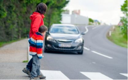 photo of a woman and child crossing the street with a car waiting