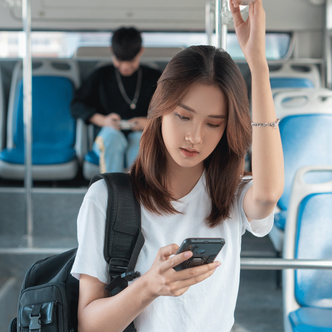 girl looking at her cell phone while on a bus