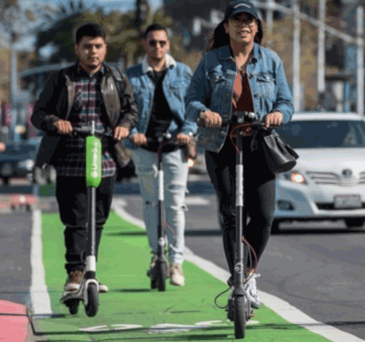 three people riding scooters