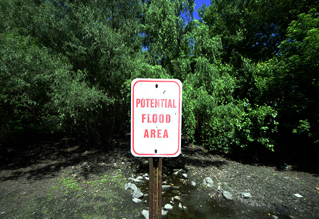 sign indicating an area that is prone to flooding in front of a flooded area