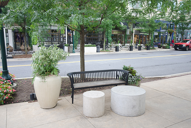 planters and a bench on a public sidewalk near a city street
