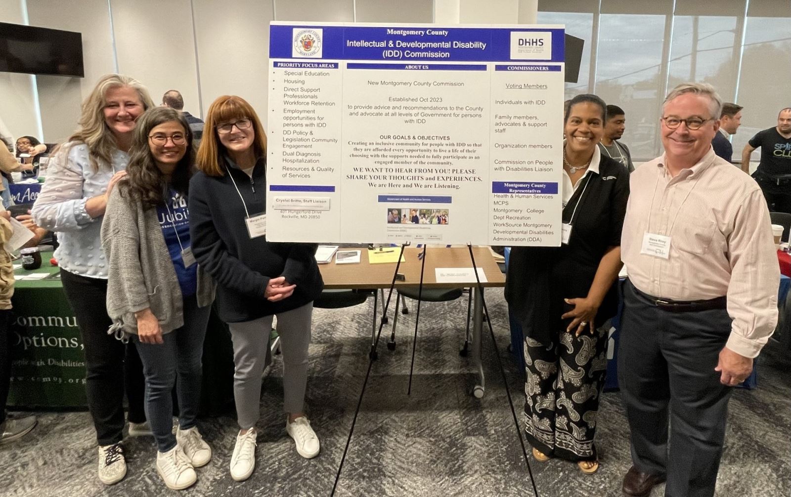 Several Commissioners at Resource Fair standing next to poster