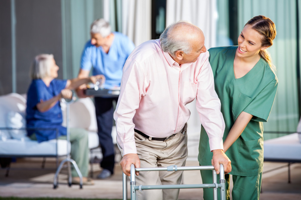 Nurses helping elders in a nursing home - nurse assisting elderly man pushing walker