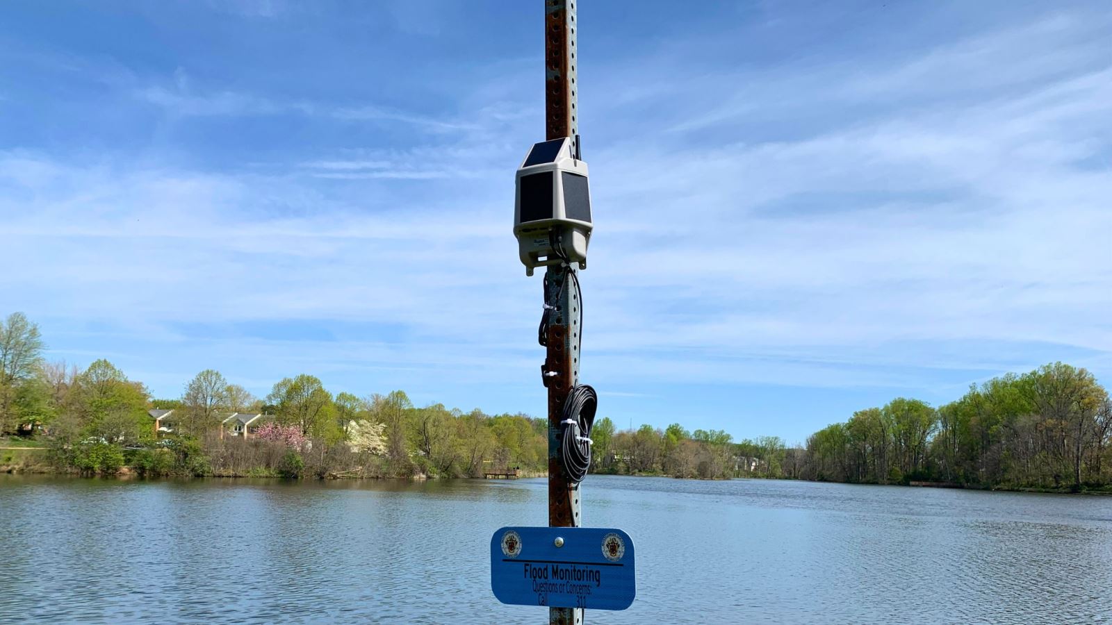 Flood sensor in residential lake with sign that has Montgomery County Maryland seal and Flood Sensor
