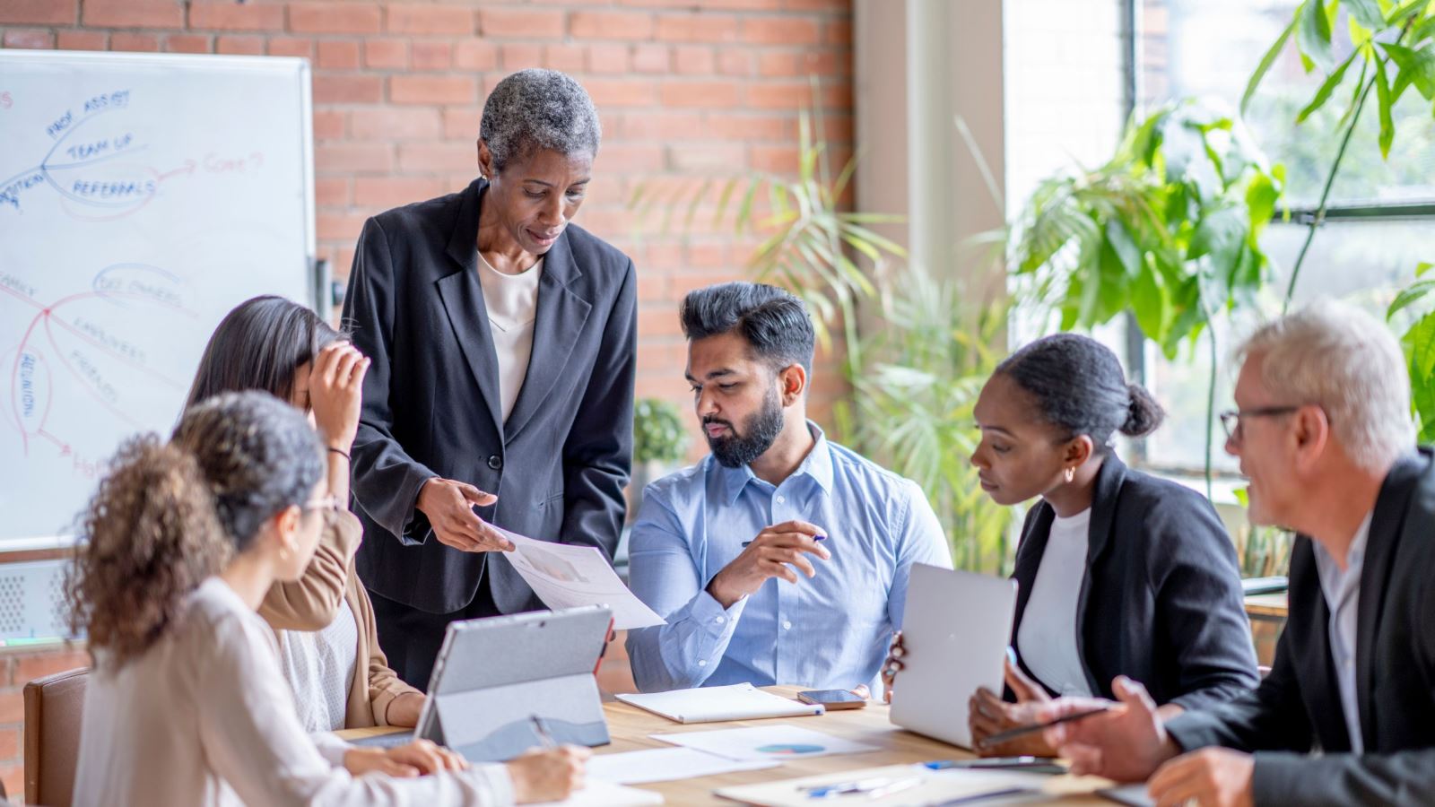 Woman standing and showing a paper with colleagues holding a planning meeting in a conference room.