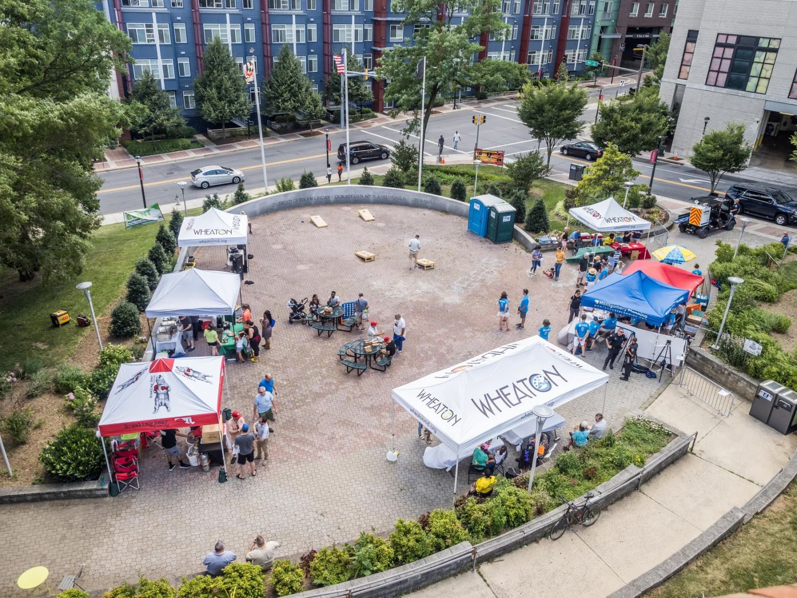 A photo of the building with an outdoor event with tents and people