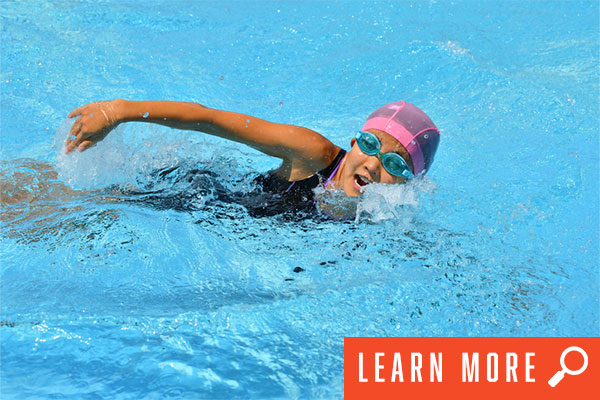 Girl in pool swimming. View swim league information.