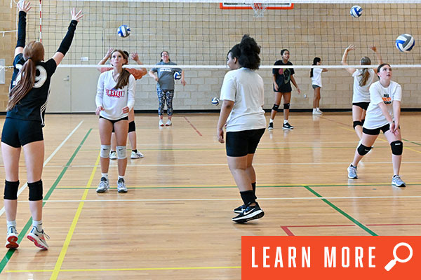 Girls playing volleyball indoors. Learn more.