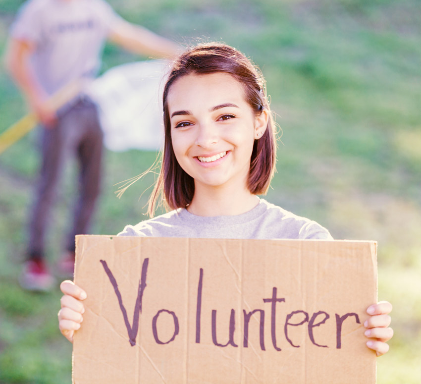 young woman holding sign that says 'volunteer'